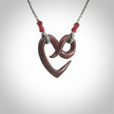 This piece is a fine, delicate eternity shaped pendant. It was carved from a lovely piece of red jasper stone. It is suspended on an grey braided cord that is length adjustable.